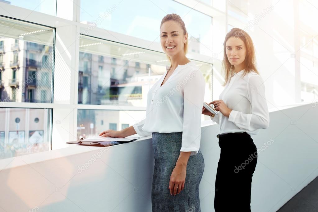businesswomen posing near office window indoors