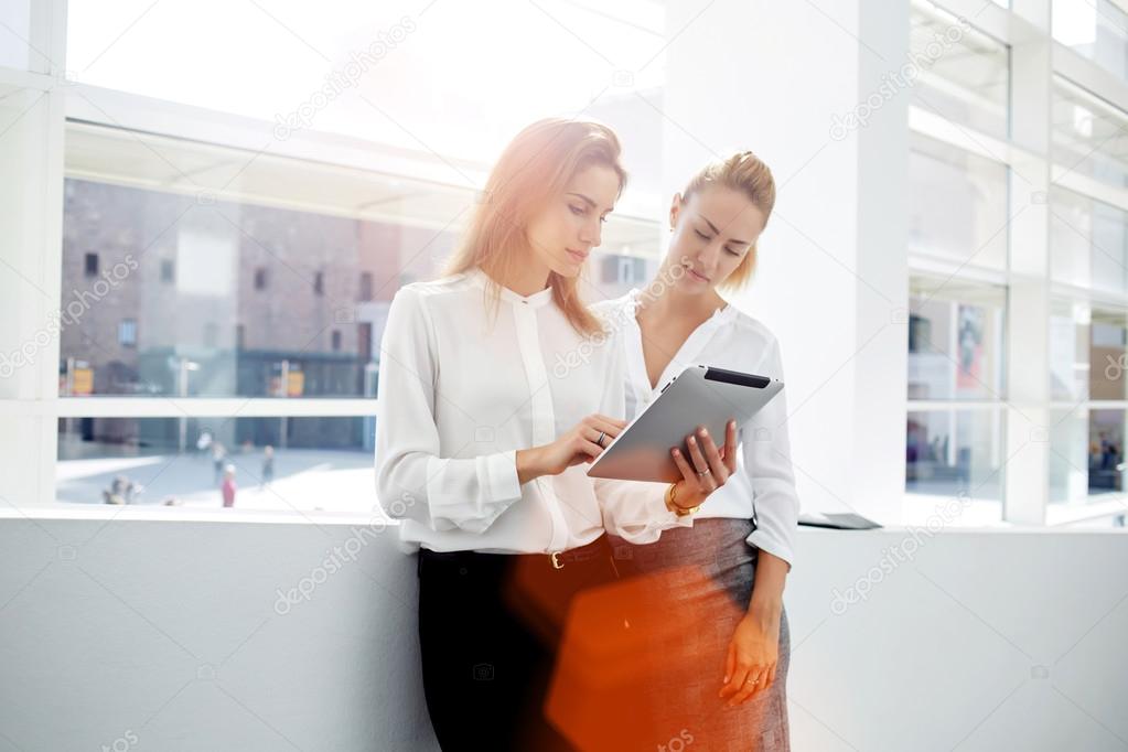 Two businesswomen working on digital tablet