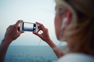 woman shoots video of sea landscape