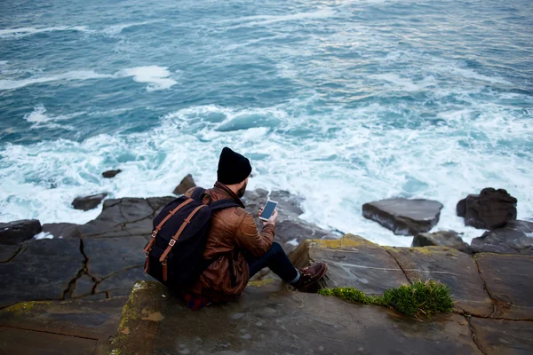 Man with backpack using mobile phone — Stock Fotó