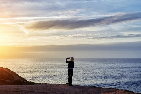 Woman photographing amazing sunset — Stockfoto