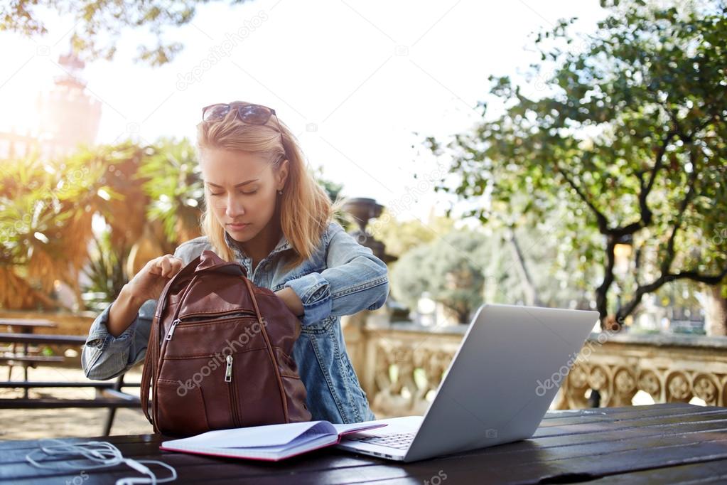 Hipster girl looking for something in bag