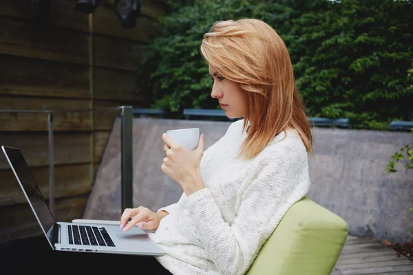 Woman reading news in network via laptop — ストック写真