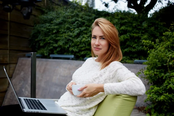 Жінка дивиться на камеру, сидячи з ноутбуком — стокове фото