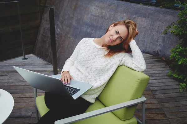 Woman looking at camera while sitting with laptop — Stockfoto