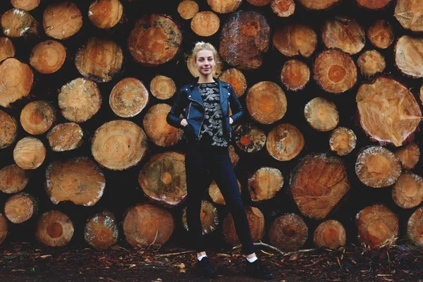 Meisje tegen gestapelde houten logboeken — Stockfoto