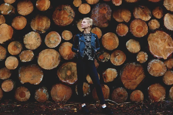 Girl against stacked wooden logs — Stock Photo, Image