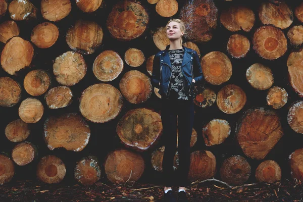 Девушка против сложенных деревянных бревен — стоковое фото