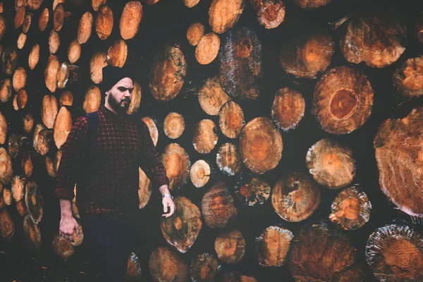 Man against stacked wooden logs — Stock Photo, Image