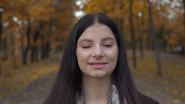 Glimlachende vrouw portret close-up naar camera, herfst park wandelen, val achtergrond — Stockvideo