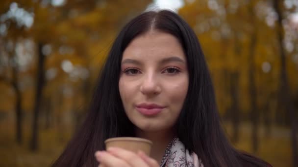 Retrato de mulher sorridente atraente, parque de outono andando ao ar livre, beber café — Vídeo de Stock