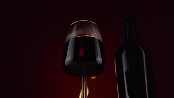 Vin en verre à vin sur fond avec feu brûlant, bouteille en verre — Video