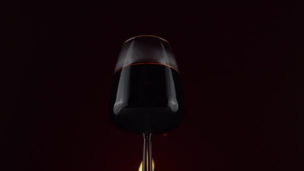 Červené víno v vinném skle na pozadí s hořícím ohněm — Stock video