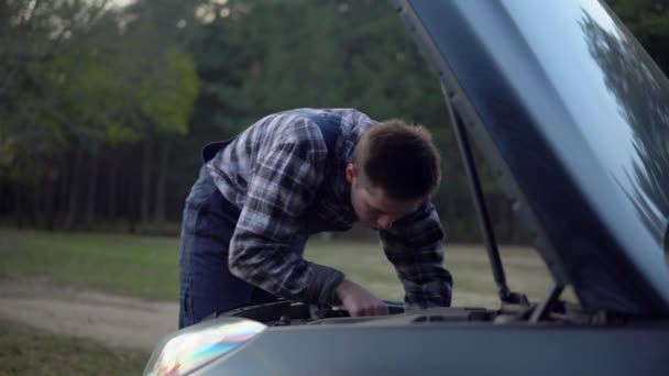 Mechanische man in uniform open motorkap bevestiging kapotte auto op bosweg — Stockvideo