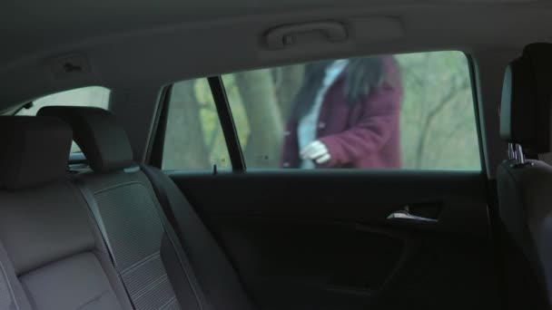 Молодая женщина в защитной маске садится на пассажирское сиденье — стоковое видео