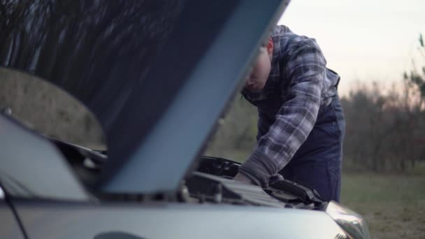 Автомеханик чинит сломанный автомобиль, открытый капот, человек в форме рабочего оборудования — стоковое видео