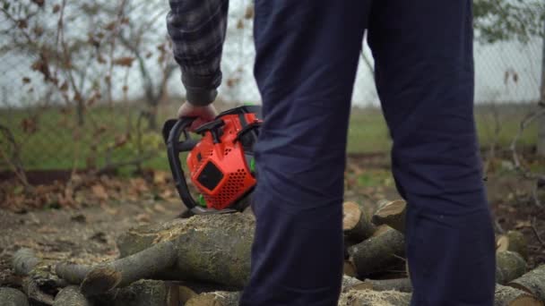 Mann startet Kettensäge und sägt Baumstamm, kümmert sich um Garten und Hausarbeit — Stockvideo