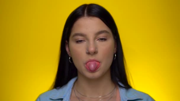 Vrouw blazen roze kauwgom bal en pop het op gele achtergrond, slow motion — Stockvideo