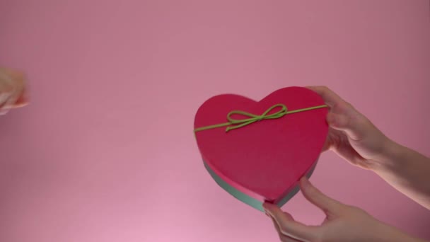 Geef st. Valentijnsdag cadeau van hand tot hand, geschenkdoos op roze achtergrond — Stockvideo