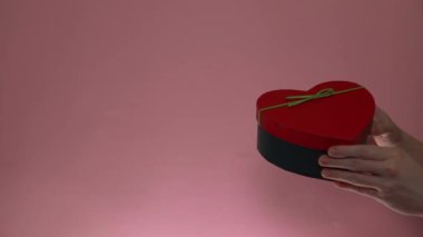 Sevgililer Günü 'nde pembe arka planda hediye kutusunu elden ele verin.