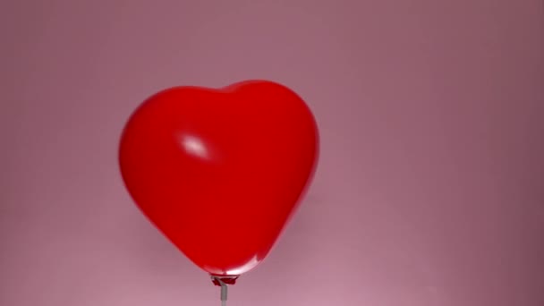 Hjärtat form ballong rotera på rosa bakgrund. St. Alla hjärtans dag koncept — Stockvideo