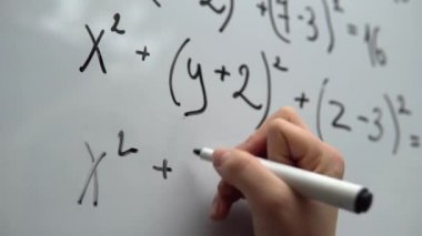 Student doing mathematic exercises, writing math equation on whiteboard 