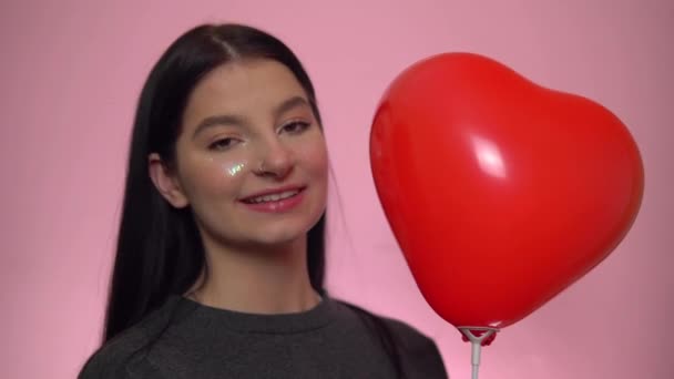 Mujer sonriente con globo rojo mirando a la cámara. Día de San Valentín — Vídeos de Stock