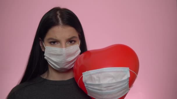 Coronavirus socialt avstånd koncept. Kvinna och ballong hjärta i skyddande mask — Stockvideo