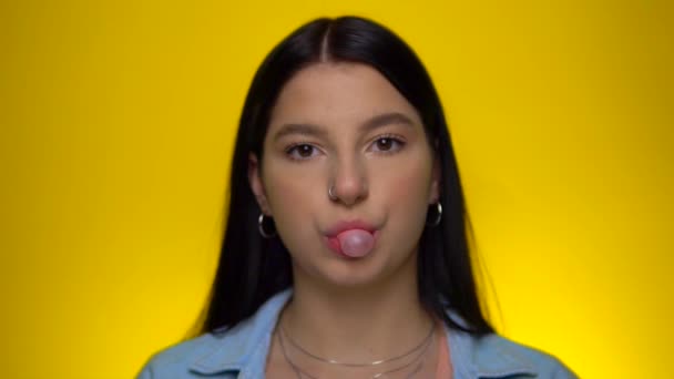 Young woman blowing bubble gum ball in slow motion, looking at camera, portrait — Stock Video