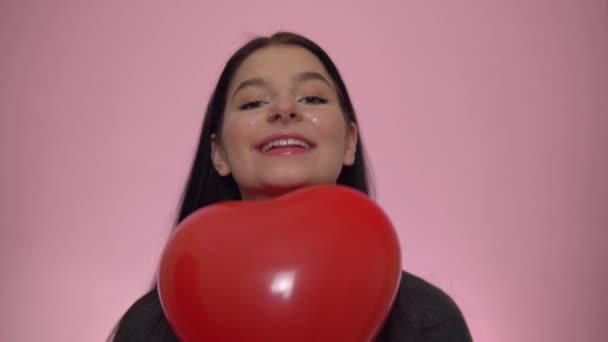 Mujer feliz sonriente con corazón de globo sobre fondo rosa. Día de San Valentín — Vídeos de Stock