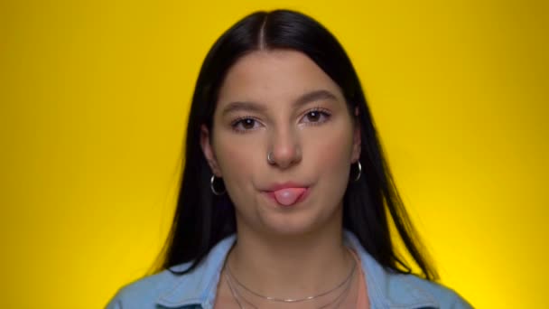 Woman with piercing nose looking at camera and blowing bubble gum in slow motion — Stock Video