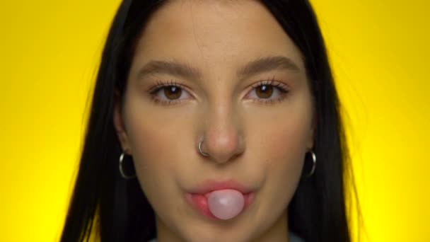 Attractive girl chawing and blowing bubble gum ball, pop it in slow motion — Stock Video