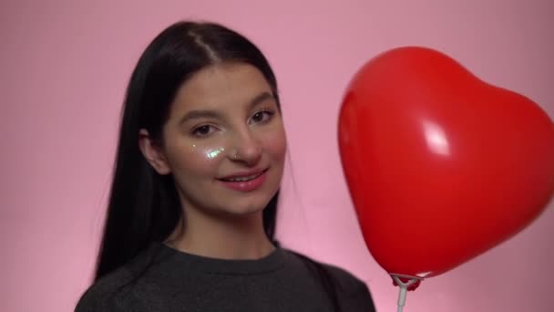 Lächelnde Frau, die in die Kamera schaut, rotes Ballonherz in der Hand. Valentinstag — Stockvideo