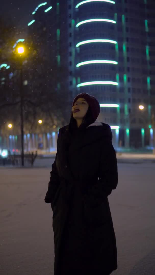 Atraktivní žena chytit sněhovou vločku ústy. Sněžná zimní procházka. vánoční nálada — Stock video