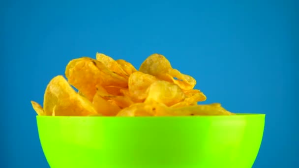 Картофельные чипсы летят в миску. Закуски крупным планом, нездоровая еда — стоковое видео