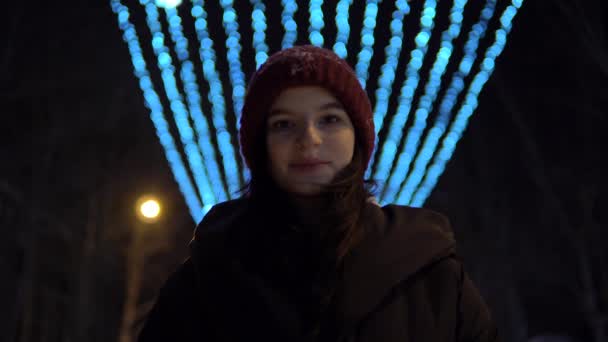 Aantrekkelijke vrouw die 's winters op straat loopt, naar de camera kijkt, glimlacht — Stockvideo