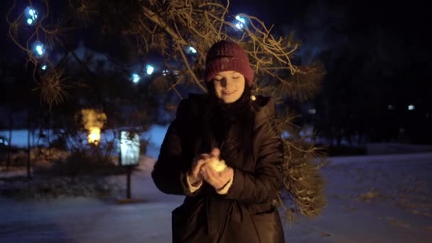 Молода жінка грає в сніжки на вулиці, зимова нігтьова ходьба в місті — стокове відео