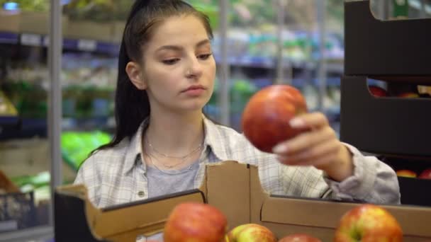 Kadın süpermarkette elma seçiyor. Meyveli raflar. Plastik paket yok. — Stok video