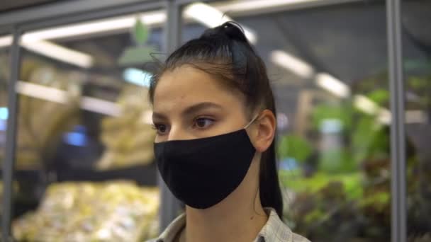 Vrouw in supermarkt met beschermend masker, op planken kijken, producten kiezen — Stockvideo