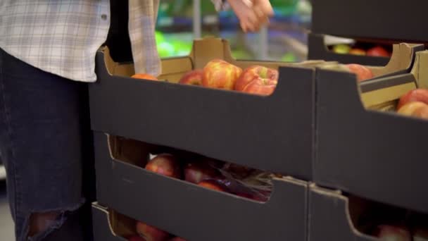Женщина в супермаркете берет яблоки из коробки. Концепция нулевых отходов и пластика — стоковое видео