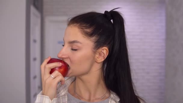 Mujer atractiva comiendo manzana roja, mirando a la cámara. Alimentación saludable, vegetariana — Vídeo de stock