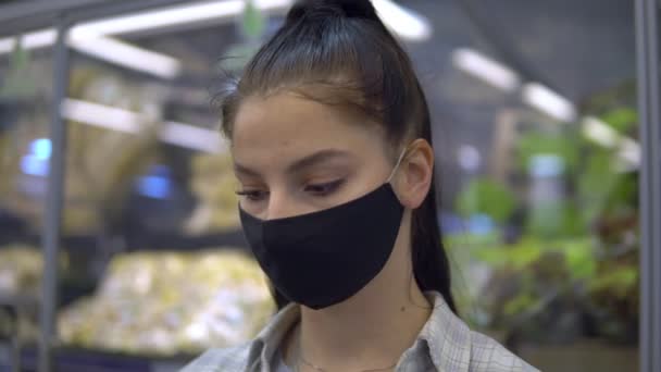 Femme en masque de protection marchant au supermarché. Recherche sur les étagères de produits — Video