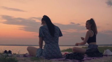 LGBT lezbiyen çifti sahilde ilişki kuruyor. Piknik randevusu olan kadınlar. Yaz tatili