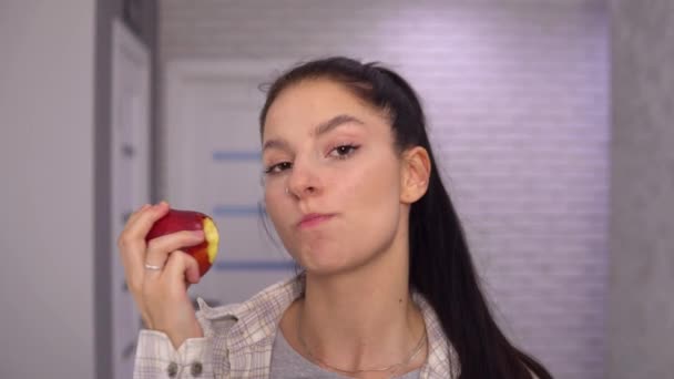 Atractiva mujer mordiendo manzana grande de cerca, mirando a la cámara, comida irritable — Vídeos de Stock