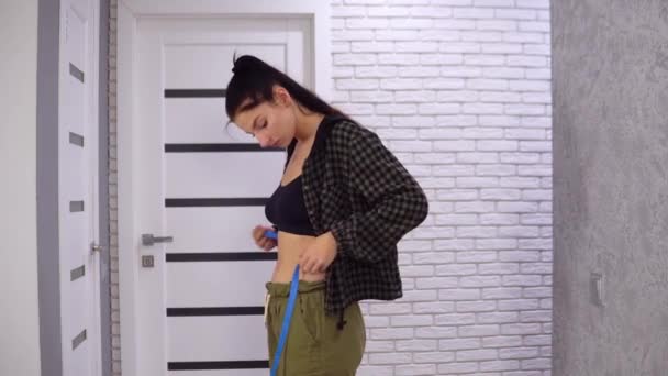 Jovem mulher medindo seu tamanho da cintura com fita métrica, conceito de dieta — Vídeo de Stock