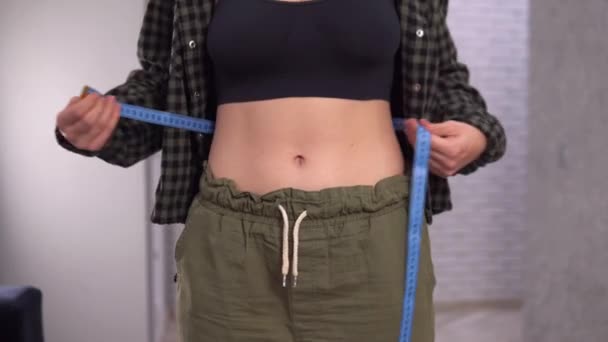 Concept de poids lâche. Femme avec gros ventre mesurant la taille de sa taille. — Video