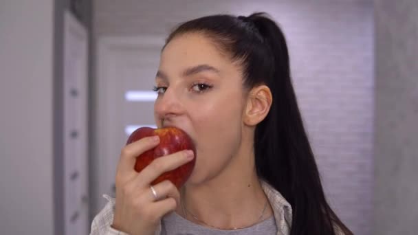 快乐的女人咬着大大的红苹果，看着相机说："好吃！. — 图库视频影像