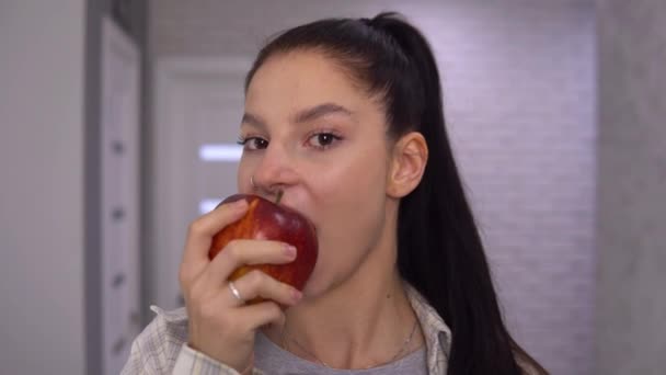 Sonriente mujer feliz mordiendo manzana roja grande. Concepto de alimentación saludable. — Vídeos de Stock