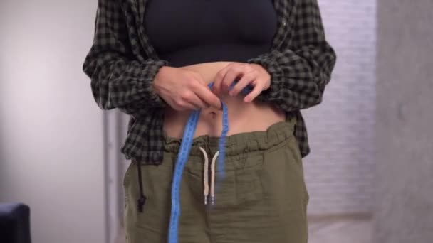 Избыточный вес женщины измеряет ее размер талии. Концепция снижения веса и диеты. — стоковое видео