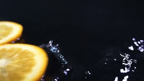 Zpomalené citron padající vodou kapky na černém povrchu.